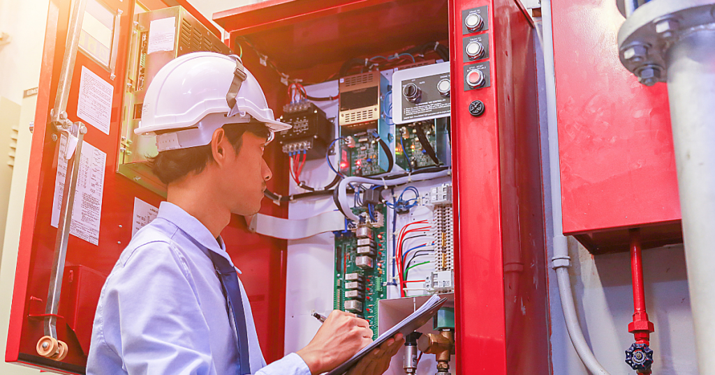 man inspecting fire alarm panel