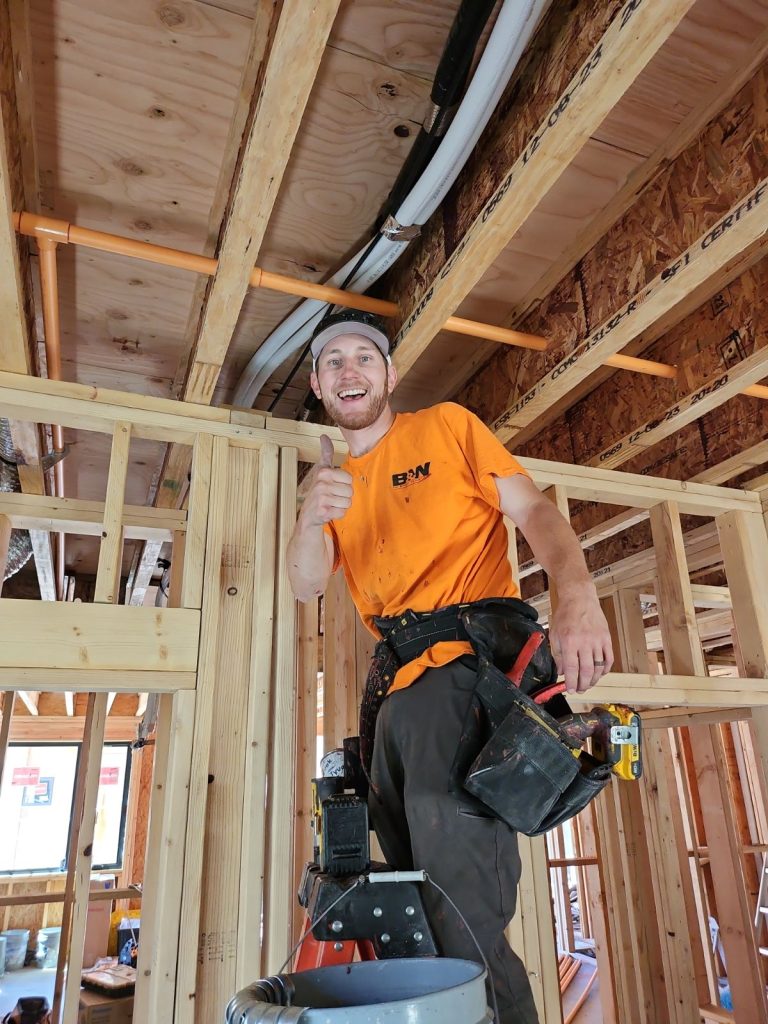 B&W Worker in an orange shirt giving a thumbs up